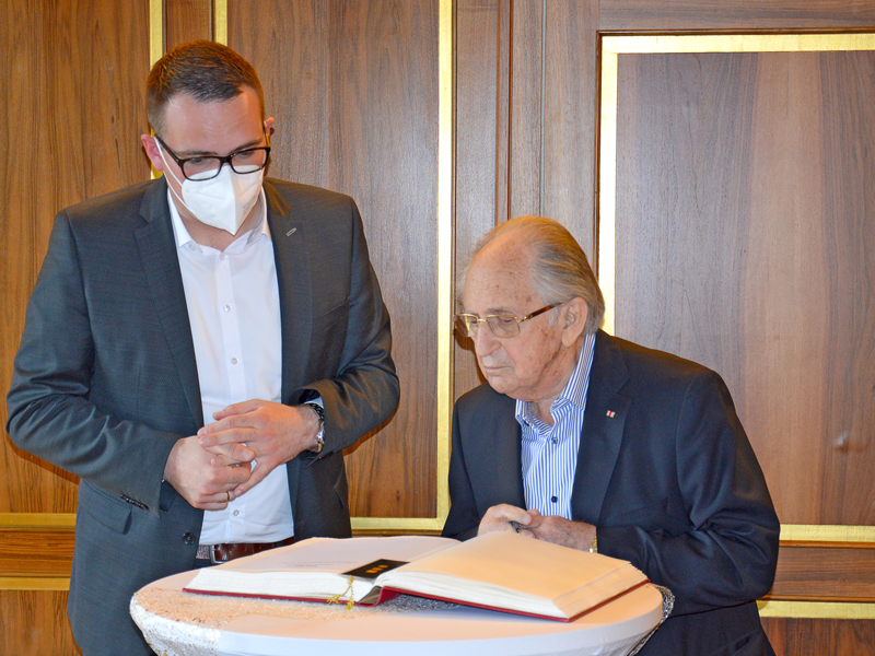 Oberbürgermeister Peter Reiß betrachtet zusammen mit Abba Naor den Eintrag in das Gästebuch.
