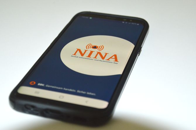 Handy, die die App NINA auf dem Display zeigt