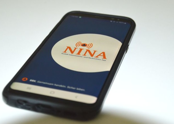 Handy, die die App NINA auf dem Display zeigt