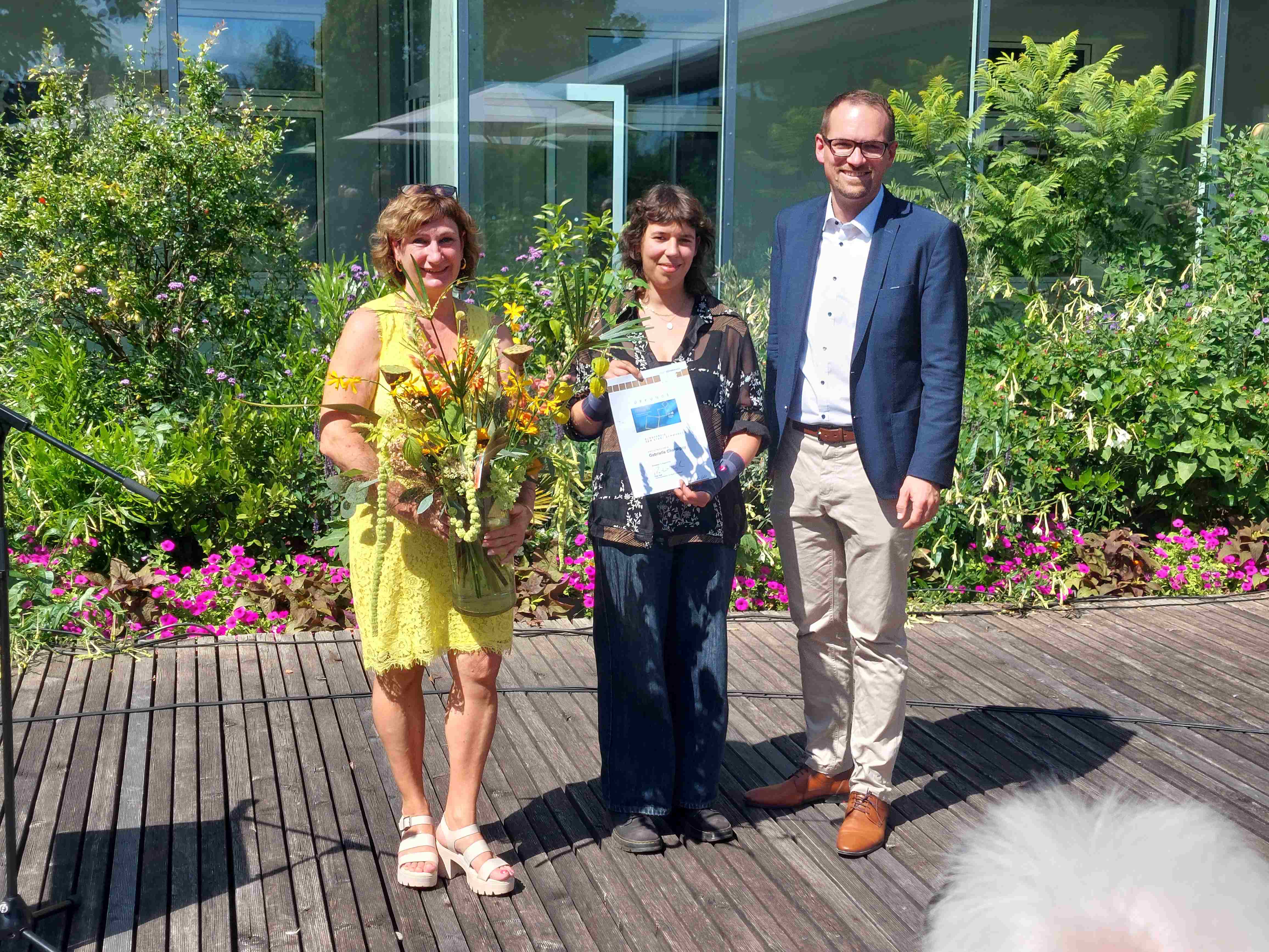 Gabrielle Chardigny (Mitte) erhält im Park des Stadtmuseums im Beisein fast aller teilnehmenden Künstlerinnen und Künstler den Jurypreis aus den Händen von Oberbürgermeister Peter Reiß und Sandra Hoffmann-Rivero (Leiterin Kulturamt Schwabach).