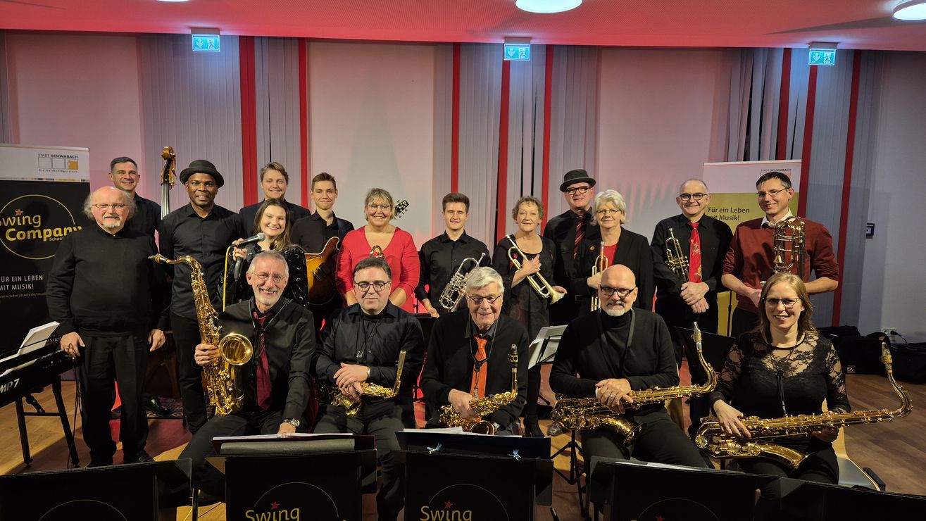 Big Band sitzt mit Instrumenten auf Bühne