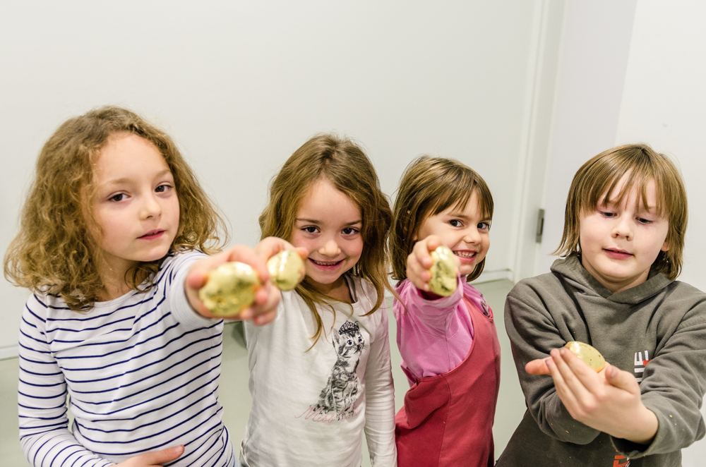 Vier Kinder zeigen in die Kamera stolz ihre handvergoldeten Eier