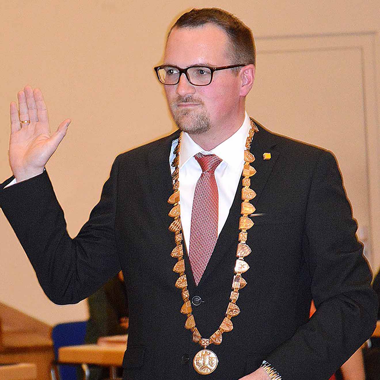 Oberbürgermeister Reiß mit goldener Amtskette um den Hals hebe die rechte Hand bei der Vereidigung