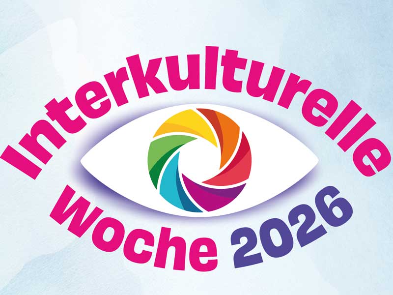Stilisiertes Auge, dessen Iris in Regenbogenfarben dargestellt ist. Darüber steht in pinkfarbener Schrift "Interkulturelle", darunter "Woche" in Pink und "2026" in Blau.