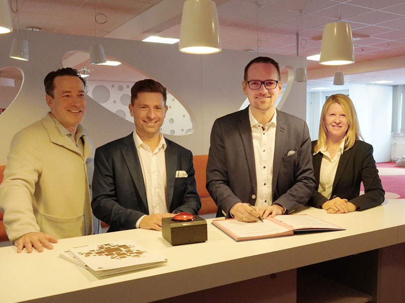 Die Gruppe beim Unterzeichnen der Absichtserklärung an einer Theke im Veranstaltungsraum der "Jungen Unternehmen Wallenrodstraße"