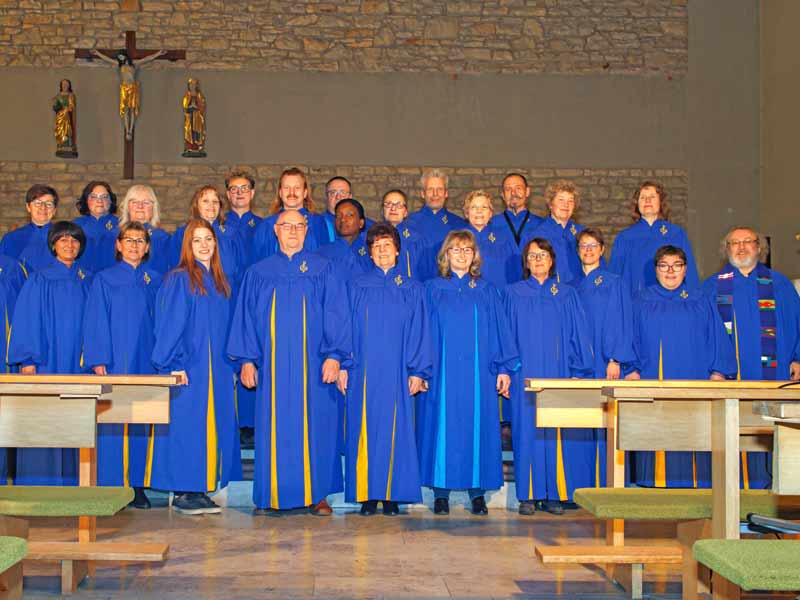 Männer und Frauen in blauen Roben, die in zwei Reihen hintereinander in einer Kirche stehen.